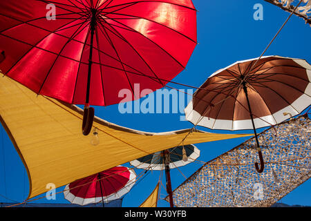 Parasols colorés sur fond de ciel bleu couvrant taverna terrasse dans village de Vasiliki, Crète, Grèce Banque D'Images