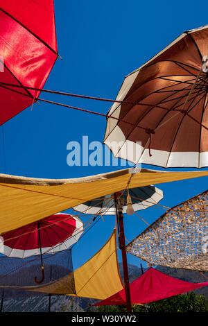 Parasols colorés sur fond de ciel bleu couvrant taverna terrasse dans village de Vasiliki, Crète, Grèce Banque D'Images