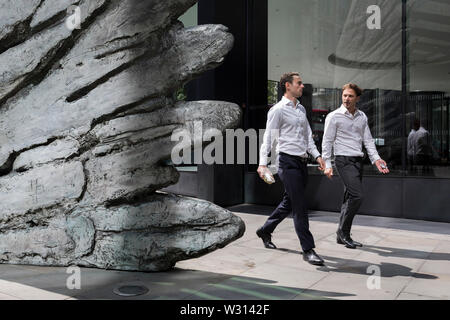 Les hommes d'affaires de l'industrie financière à pied au-delà de la sculpture intitulée City Wing sur Threadneedle Street dans la ville de Londres, le quartier financier de la capitale (aka le Square Mile), le 11 juillet 2019, à Londres, en Angleterre. L'aile est de la ville par l'artiste Christopher Le Brun. Les dix mètres de haut est la sculpture en bronze par le président de la Royal Academy of Arts, Christopher Le Brun, commandé par Hammerson en 2009. Elle est appelée 'La Ville' de l'aile et a été jeté par Morris Singer, fondateurs de l'art réputé pour être la plus ancienne fonderie d'art dans le monde. Banque D'Images