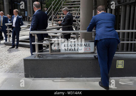 Les gens d'affaires de l'industrie de l'assurance de recueillir à l'extérieur du bâtiment Lloyds of London sur leadenhall Street dans la ville de Londres, le quartier financier de la capitale (aka le Square Mile), le 10 juillet 2019, à Londres en Angleterre. Banque D'Images