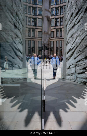 Les hommes d'affaires de l'industrie financière à pied au-delà de la sculpture intitulée City Wing sur Threadneedle Street dans la ville de Londres, le quartier financier de la capitale (aka le Square Mile), le 11 juillet 2019, à Londres, en Angleterre. L'aile est de la ville par l'artiste Christopher Le Brun. Les dix mètres de haut est la sculpture en bronze par le président de la Royal Academy of Arts, Christopher Le Brun, commandé par Hammerson en 2009. Elle est appelée 'La Ville' de l'aile et a été jeté par Morris Singer, fondateurs de l'art réputé pour être la plus ancienne fonderie d'art dans le monde. Banque D'Images