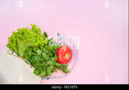 Verdure fraîche et les légumes dans un sac écologique sur fond de couleur rose avec copyspace. Concept de saine alimentation. Banque D'Images