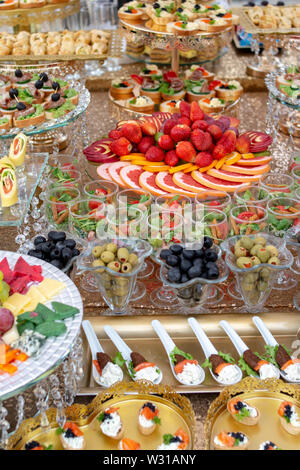 Grande sélection d'aliments contenant des collations froides, viandes et salades, fruits, charcuterie, fromage et confiture servi. Variété de délicieux en-cas savoureux sur la table. Banque D'Images