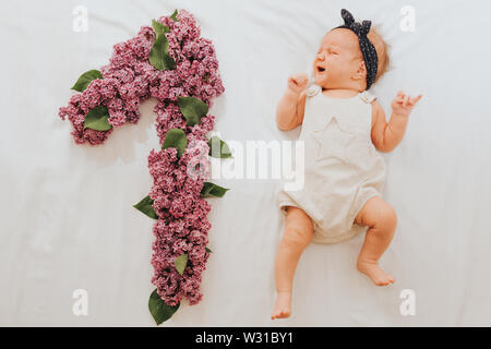 Télévision jeter la photo d'un bébé de 1 mois avec plusieurs faits de feuilles de chêne et de fleurs lilas Banque D'Images