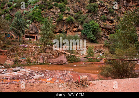 Berbère de montagne locaux passerelle au-dessus de la rivière boueuse dans les montagnes de l'atlas du Maroc rural scene Banque D'Images