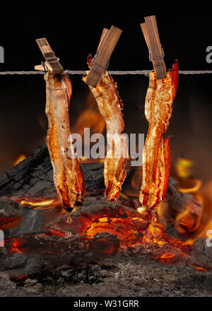 Et raosting smopking sur feu ouvert avec bacon de porc côtes levées et les cuisses de poulet Banque D'Images