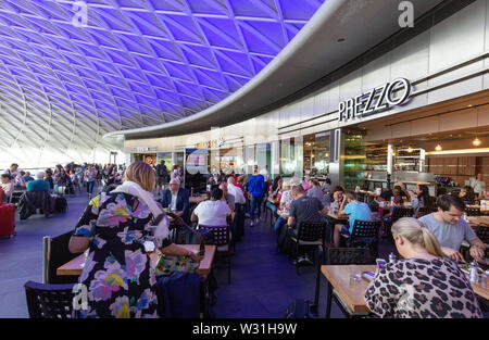 Hall de la gare de Kings Cross, London UK - les gens assis à manger cafés sur le grand hall, Kings Cross Londres Angleterre Banque D'Images
