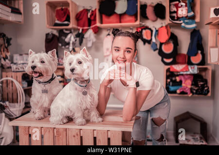 Près de cute chiens. Aux yeux sombres Cute woman wearing white t-shirt debout près de mignons petits chiens Banque D'Images