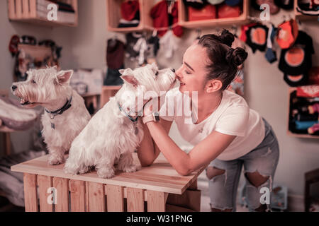 Chien blanc moelleux. Aux yeux sombres Cute woman wearing smart watch jouant avec fluffy white dog Banque D'Images