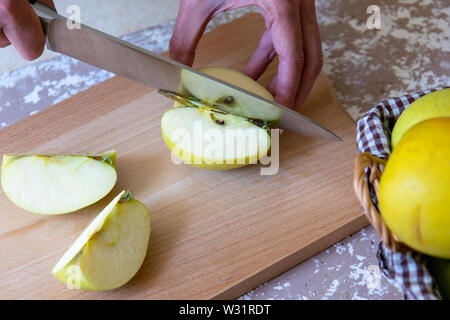 Coupe Femme au couteau une pomme à tranches sur une planche à découper sur une table dans la cuisine. Pommes Chantecler. La cuisson des aliments. Banque D'Images