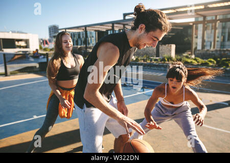 Les amis jouant au basket-ball jeu sur une journée ensoleillée sur cour de la rue. Groupe d'amis pratiquant le basket-ball ses dribbles sur rue. Banque D'Images