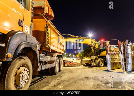 Valencia, Espagne - 4 juillet 2019 : un camion à côté d'une excavatrice garé la nuit dans un projet d'assainissement dans une ville. Banque D'Images