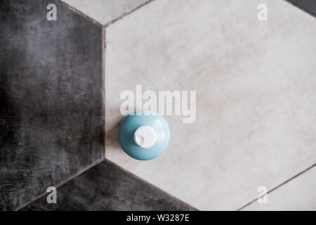 Bouteille en plastique de couleur bleu clair sur le carrelage blanc et gris. Le minimalisme du design. Vue de dessus, copyspace Banque D'Images