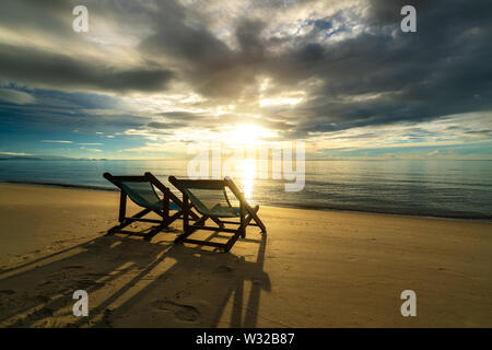 Deux chaises longues sur la plage au coucher du soleil avec une mer tropicale arrière-plan. Voyages et vacances dans l'été en mer. Banque D'Images