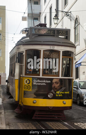 Tramway vintage jaune et blanc sur le Tram 28 (route 552) voiture vers l'ouest en descente sur des rues pavées ville rue à Rua Vitor Cordon Lisbonne, Portugal Banque D'Images