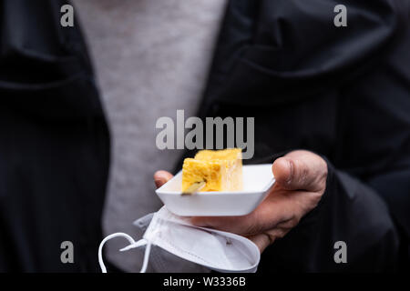 Libre de personne hands holding tamagoyaki oeufs omelette roulée japonais à Ginza Street poissons de Tsukiji marché extérieur avec personne Banque D'Images