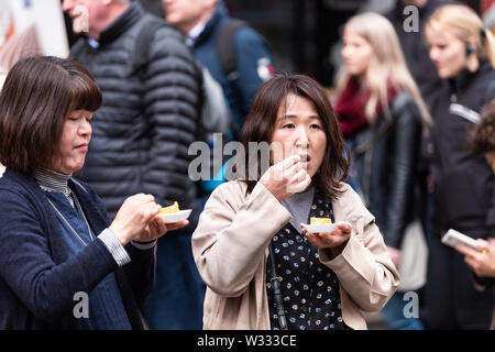 Tokyo, Japon - 30 mars 2019 : deux femmes chinois asiatique japonais tamagoyaki manger oeufs omelette roulée à Ginza rue Marché aux poissons de Tsukiji extérieur Banque D'Images