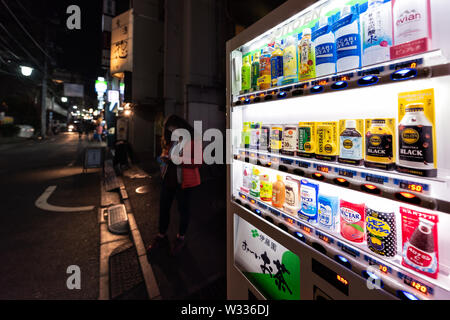 Shinjuku, le Japon - 4 Avril, 2019 : Automatique distributeur de boissons alcoolisées dans des bouteilles d'eau, café et jus avec femme gens debout sur s Banque D'Images