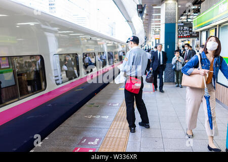 Tokyo, Japon - 4 Avril 2019 : chef d'orchestre japonais sur la plate-forme des travailleurs de la gare JR Shinjuku en train à grande vitesse Shinkansen ou avec des gens d'affaires Banque D'Images