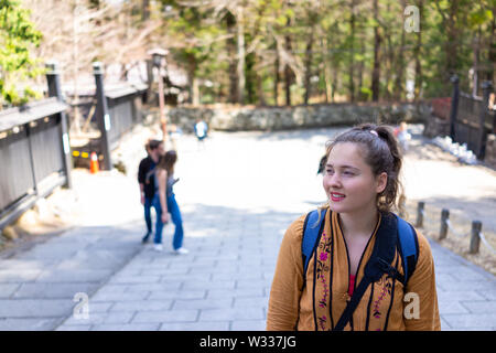 Young smiling woman, portrait étranger traveler walking in Nikko, au Japon, le chemin de la rue par la forêt au printemps Banque D'Images