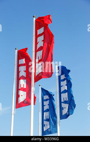 Huddinge, Suède - 11 juillet 2019 : un groupe de quatre drapeaux et mâts de Ikea sur le fond bleu ciel clair à l'extérieur du magasin à Kungens Kurva. Banque D'Images