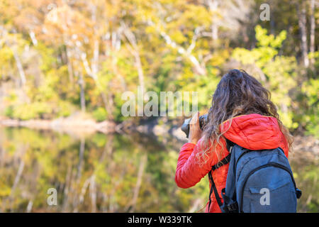 Jeune femme photographe avec sac à dos et appareil photo en photo, la photographie Grand Falls feuillage de l'automne avec vue rivière reflet dans le Maryland Banque D'Images