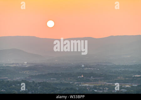 Roanoke aerial cityscape downtown view on city in Virginia with blue ridge mountains during sunset with big sun on clear day Banque D'Images