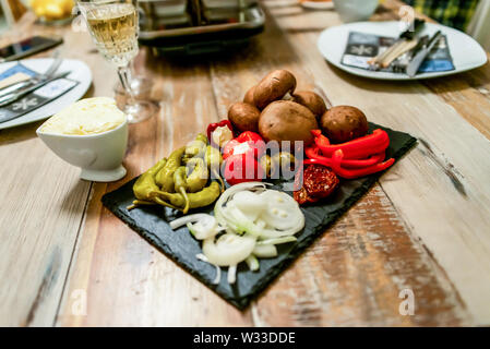 Apéritif Antipasti sweet cherry mini poivrons farcis au fromage feta et oignons sur la plaque d'ardoise. Banque D'Images