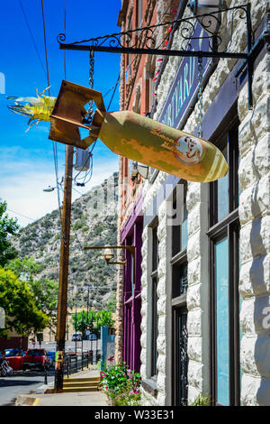 Un vieux rusty WWII bombe aérienne converti à l'art avec pinup girl suspendue au bout d'un autocollant metal sign frame passage près de l'entrée de cour, il Bisbee, AZ Banque D'Images