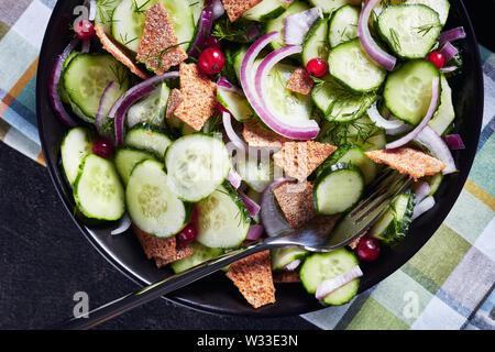 Close-up d'une partie de l'été délicieux salade de concombre, de groseille rouge, oignon rouge mariné et Crisp, tous faits de morceaux dans un bol noir, flatlay, mac Banque D'Images