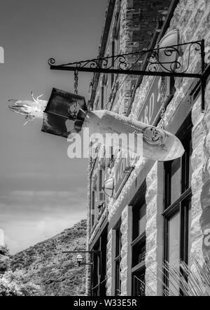 Un vieux rusty WWII bombe aérienne converti à l'art avec pinup girl suspendue au bout d'un autocollant metal sign frame passage près de l'entrée de cour, il Bisbee, AZ Banque D'Images