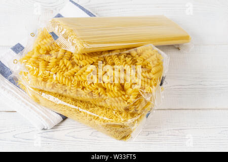 Diverses pâtes dans des sacs en plastique transparents sur une table de cuisine. Produits d'épicerie. Spaghetti, fusilli et les vermicelles. Banque D'Images