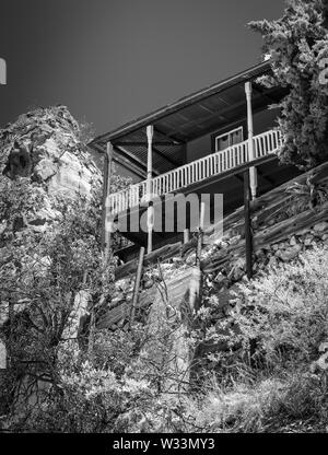 Typique de la zone, un cadre coloré, fantasque, maison avec porche enveloppant perché sur une colline avec vue sur l'aménagement paysager, Bisbee, AZ Banque D'Images