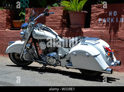 Un beau blanc Indian Motorcycle stationné dans une zone de stationnement interdit à proximité d'un mur de briques avec jardin dans le sud-ouest de l'USA, Banque D'Images