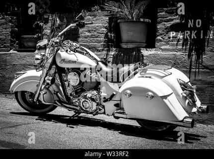 Un beau blanc Indian Motorcycle stationné dans une zone de stationnement interdit à proximité d'un mur de briques avec jardin dans le sud-ouest de l'USA, Banque D'Images