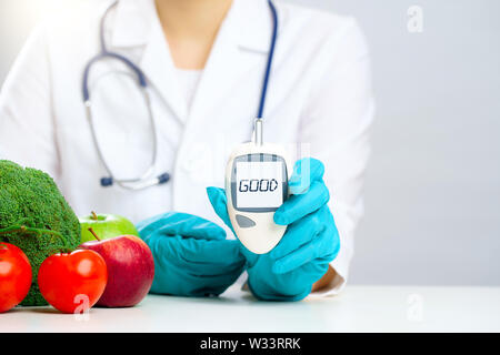 Photo de médecin en blouse et des gants en caoutchouc avec diabete avec bonne inscription à table avec des légumes sur fond gris en studio Banque D'Images