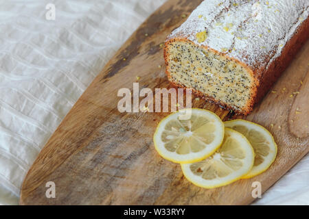 Gâteau aux Graines de pavot et le zeste de citron, saupoudrés de sucre en poudre. Cupcake au citron sur une planche en bois Banque D'Images