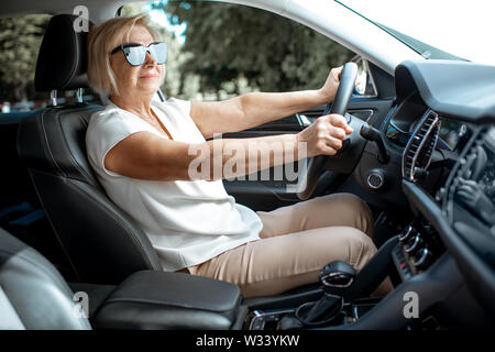 Senior business woman driving a car, vue de l'intérieur d'un véhicule. Concept d'une population active au cours de l'âge de la retraite Banque D'Images