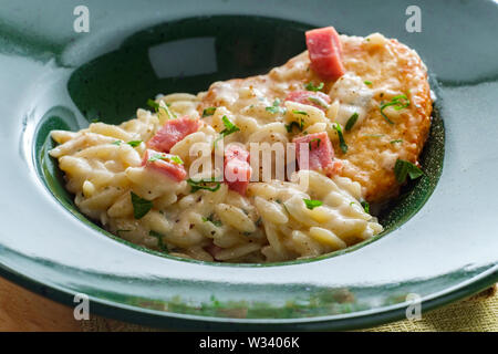 Poulet cordon bleu servi avec risotto d'orzo crème et jambon Banque D'Images