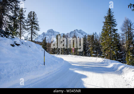 La neige a couvert vide route de montagne dans les Alpes sur une journée d'hiver ensoleillée Banque D'Images