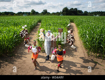 Farmer Tom Pearcy habillé comme le babouin (Mandrill) personnage du Roi Lion, est rejoint par le puissant groupe performance Zulu Nation, vêtus de costumes traditionnels Zulu, lors du lancement de la New York 2019 New York en labyrinthe, créée à partir de plus d'un million de plants de maïs de plus en plus, vivant, fêter 25 ans de The Lion King. Banque D'Images