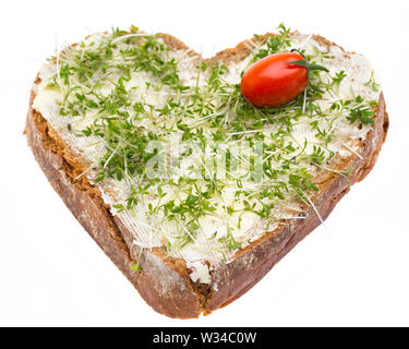 Un pain garni avec du beurre, cresson et une tomate en forme de coeur Banque D'Images
