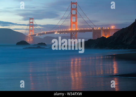 Vue panoramique classique du célèbre Golden Gate Bridge Pittoresque Baker Beach dans une belle lumière dorée le soir sur un coucher de soleil avec ciel bleu et nuage Banque D'Images