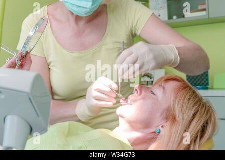Vue rapprochée d'une femme travaillant à son dentiste dents du patient dans un bureau de dentiste. Banque D'Images