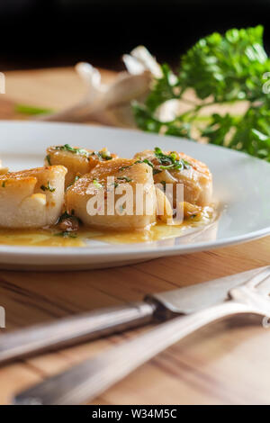 Pétoncles poêlés dans un Portugais blanc vin blanc sauce à l'ail citron Banque D'Images