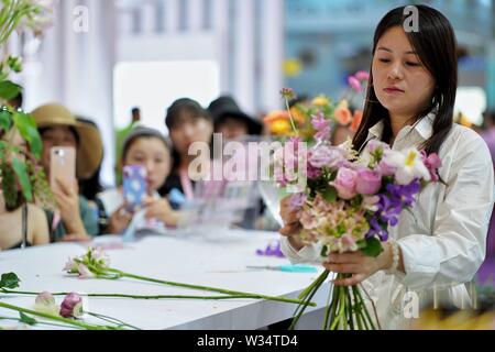 Kunming, province chinoise du Yunnan. 12 juillet, 2019. Un invité organise des fleurs au cours de la 20e International Kunming Expo Fleurs de Chine à Kunming International Dianchi Convention and Exhibition Centre à Kunming, capitale du sud-ouest de la province chinoise du Yunnan, le 12 juillet 2019. Plus de 400 exposants de 19 pays assistent à l'expo qui a donné le coup d'ici vendredi. Credit : Qin Qing/Xinhua/Alamy Live News Banque D'Images
