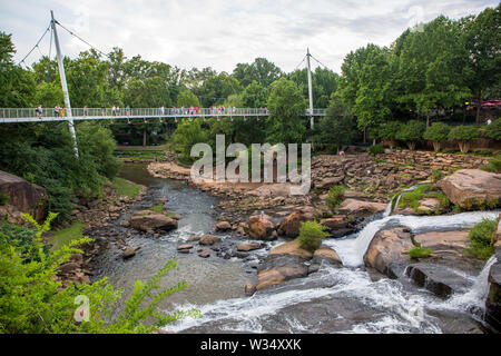 Les visiteurs de Falls Park s'attardent sur pont de la liberté qui donne sur la rivière au centre-ville de cascades de roseaux de Greenville en Caroline du Sud. Banque D'Images