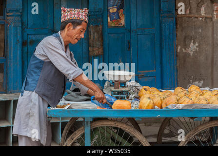 Coupe homme mango sur son panier alimentaire à Katmandou Banque D'Images