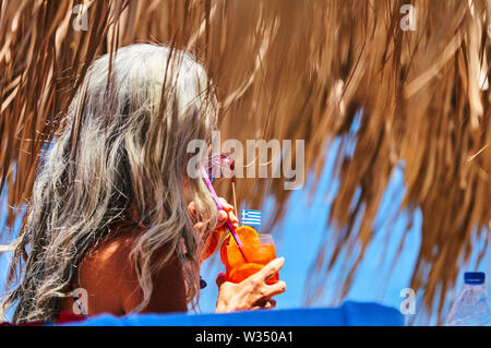 Tourist femme aux longs cheveux gris boit un cocktail à la plage de Kamari près de Oia et Fira, Santorini , Grèce au 01.06.2019. © Peter Schatz / Alamy Stock Banque D'Images