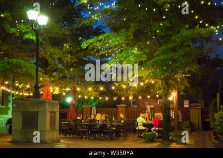 GREENVILLE, SC (USA) - 5 juillet 2019 : Les gens de manger à la terrasse d'un café après la tombée de la nuit au centre-ville de Greenville. Banque D'Images